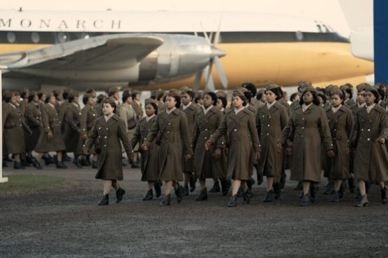 Women in WW2 army uniform march in front of an airplane
