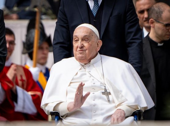 Pope Franics waves to the crowd from a wheelchair