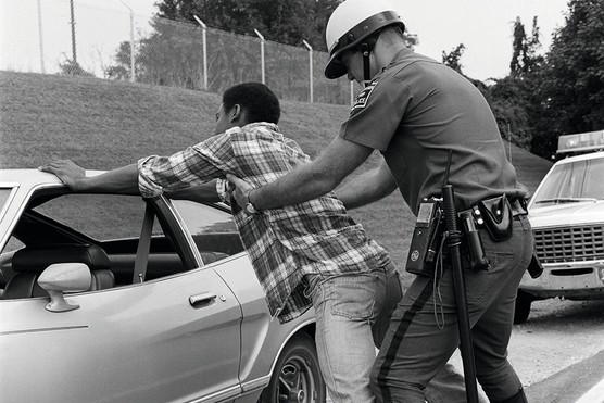 A policeman searches an African-American man, 1970s