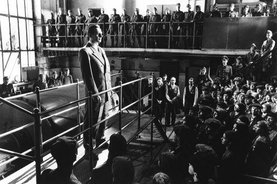 A man stands on a platform in front of a crowd