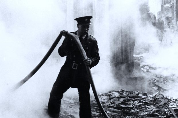 ww2-blitz-gordon-cummins A fireman pulls his hose through the smouldering ruins of a bombed out church in London in the Blitz.